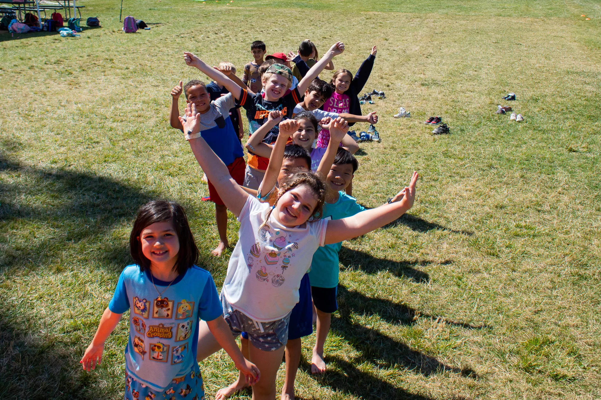 Children putting their arms up and smiling at camp