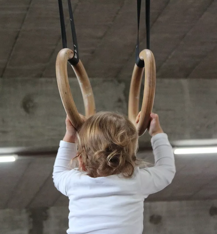 Toddler holding onto gymnastics' rings